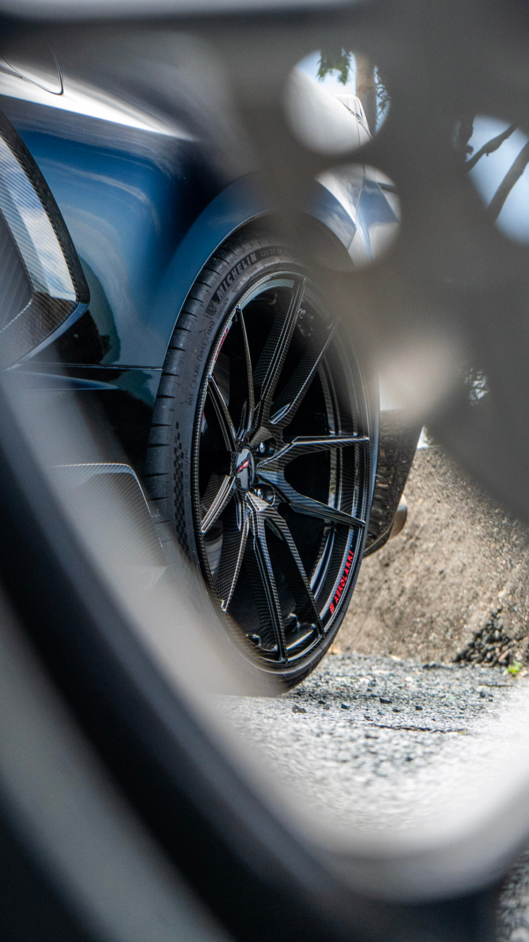 Corvette wheel framed through another car's wheel spokes