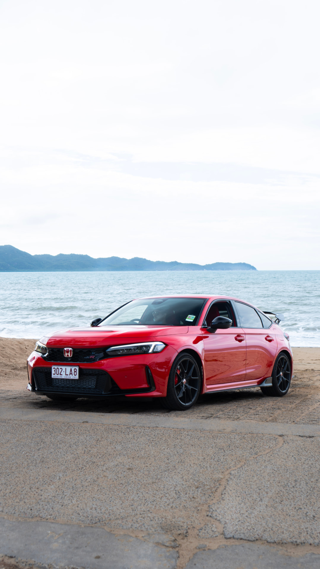 Red Honda Civic Type R parked on the beachfront