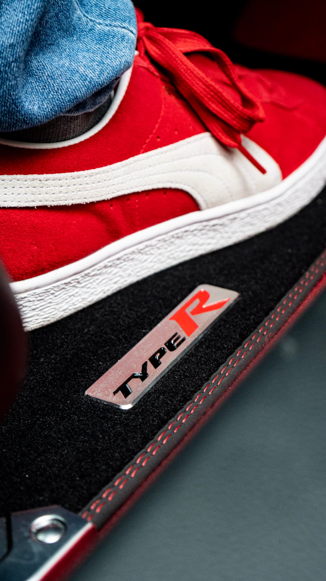 Type R door sill plate next to red suede sneakers