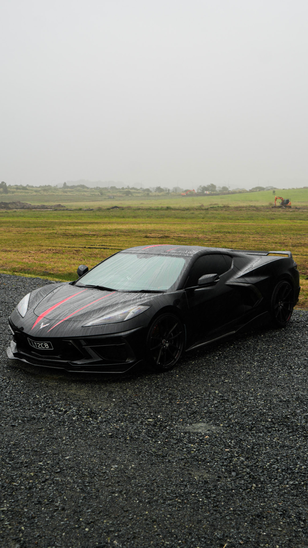 Rain-soaked Corvette C8 side profile in the mist