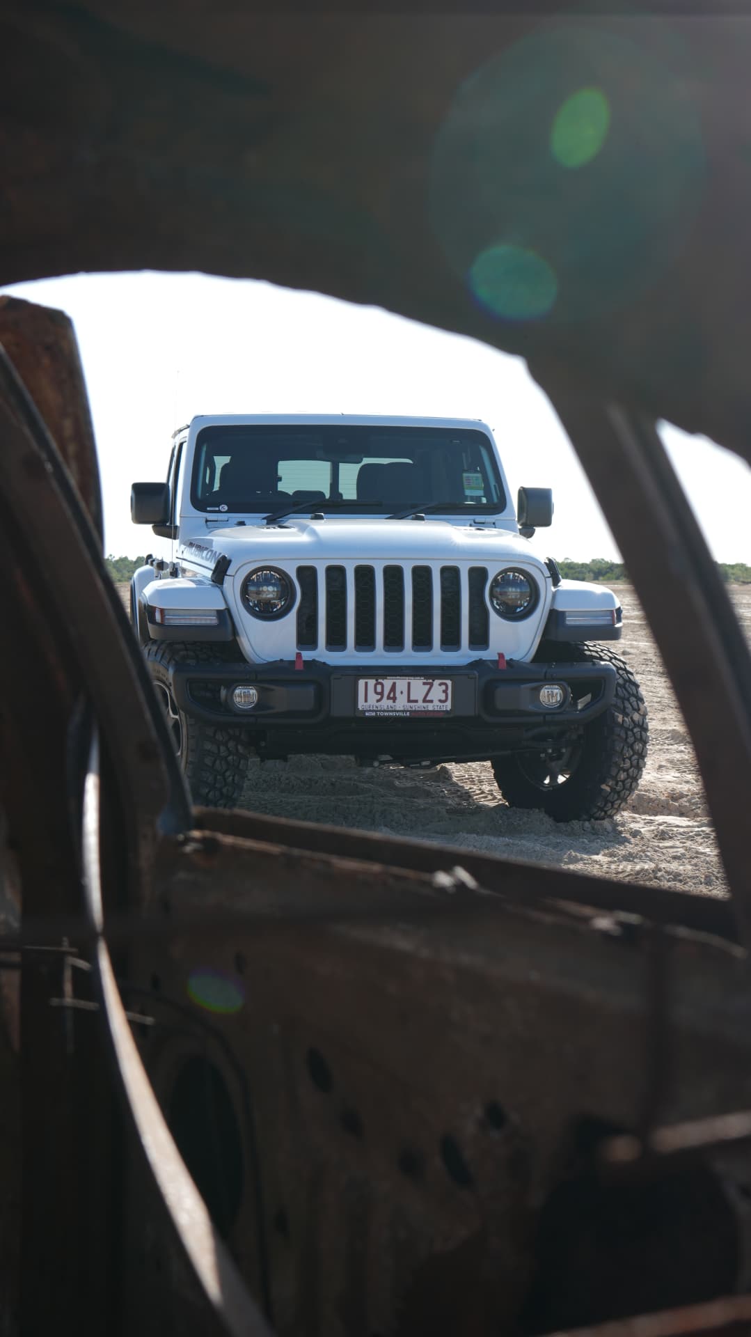 Jeep Gladiator Rubicon framed through a rusted car wreck