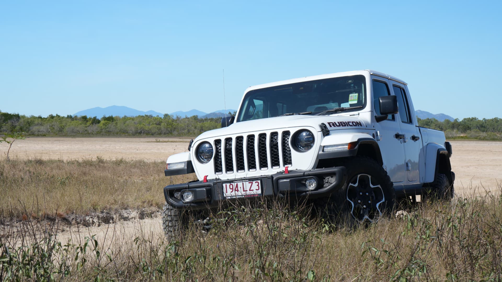 Jeep Gladiator Rubicon parked in scrub with mountains behind