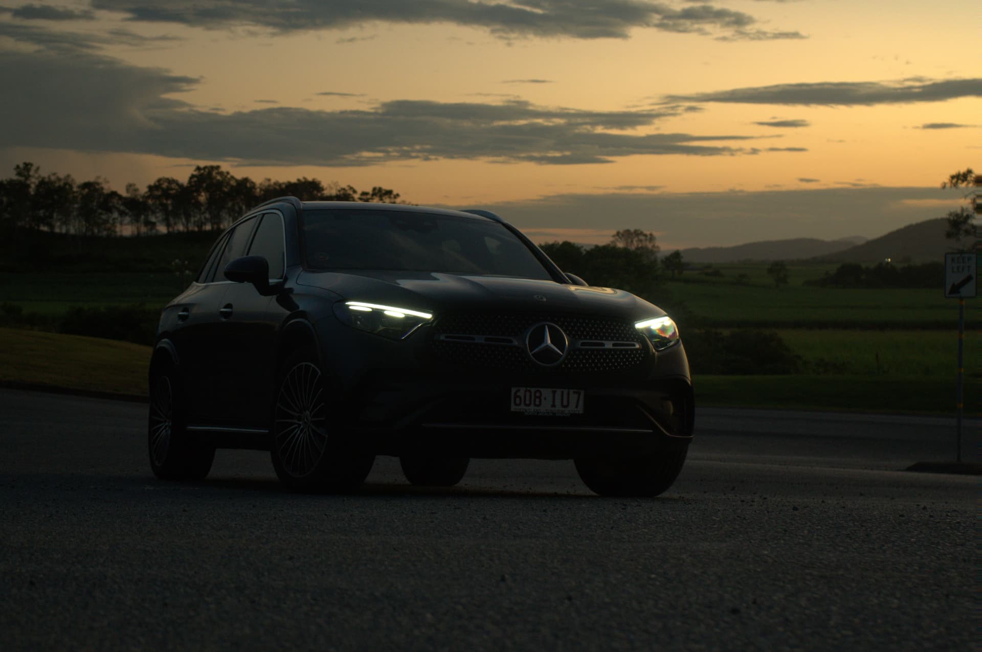 Mercedes GLC 300 front three-quarter at sunset with lights on