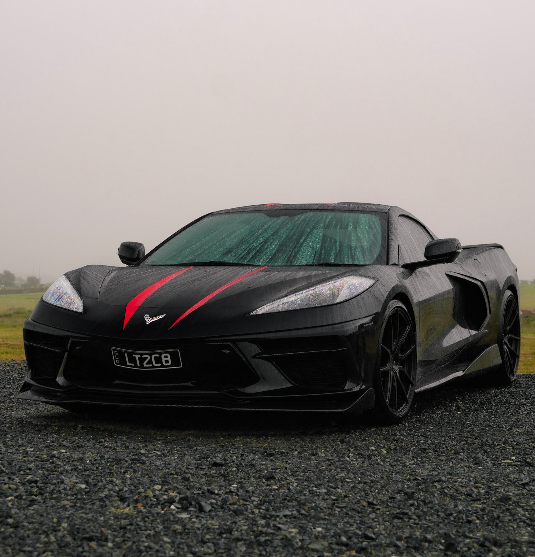 Black Chevrolet Corvette C8 with red stripes in the rain