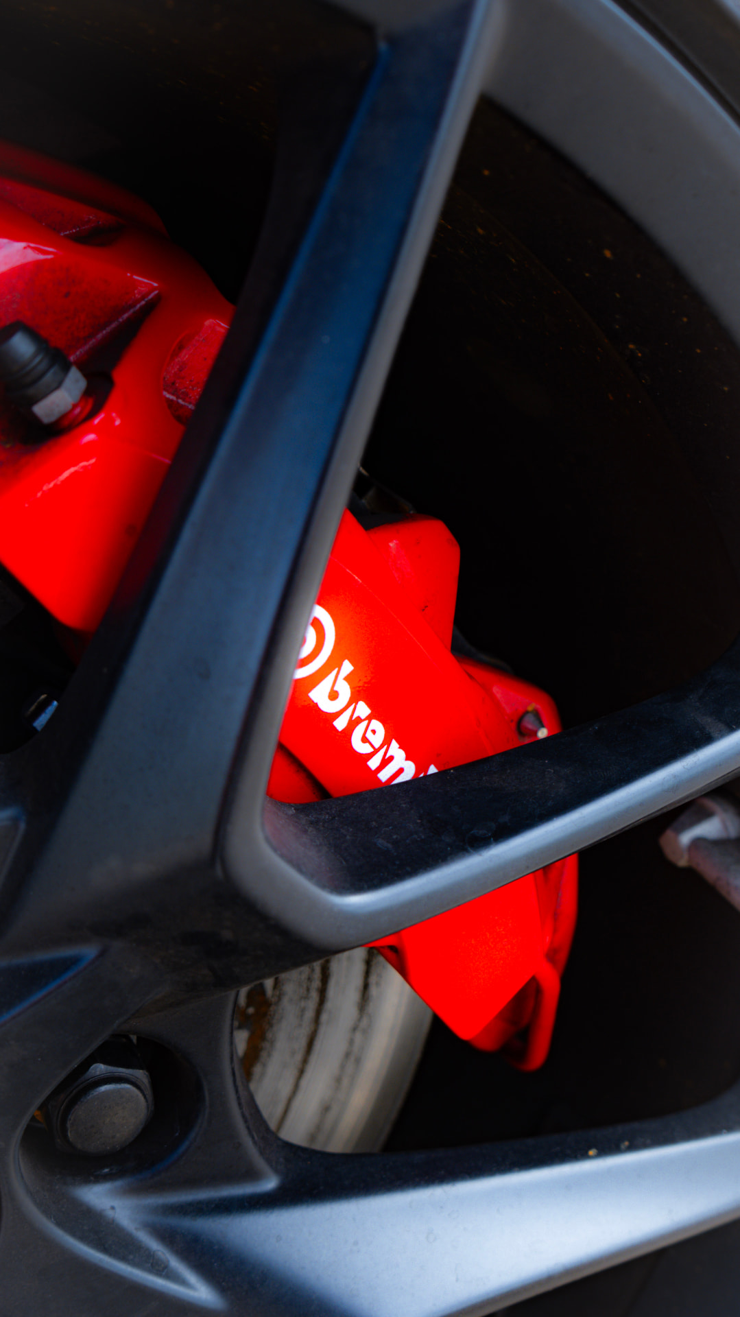 Red Brembo brake caliper behind a black alloy wheel